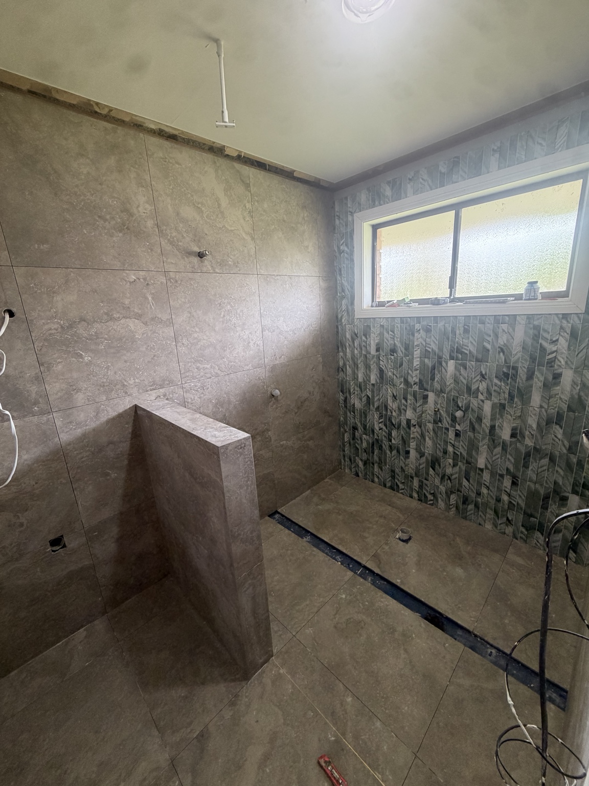 Bathroom renovation in progress with installed wall and floor tiles before fixtures and fittings are installed